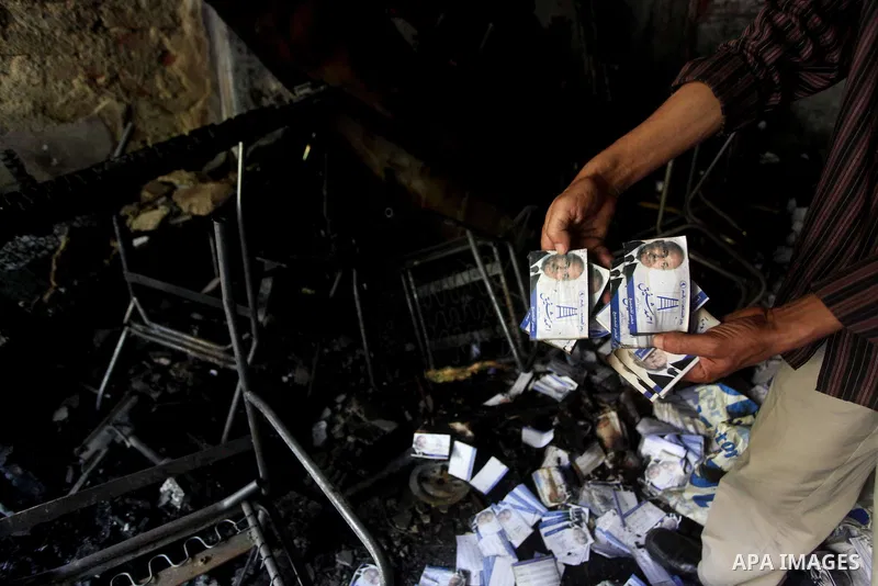 A man shows flyers of presidential candidate Ahmed Shafiq at the scene of the burnt campaign headquarters of Shafiq in Cairo May 29, 2012. A group of Egyptian protesters set fire to the headquarters on Monday, the state...