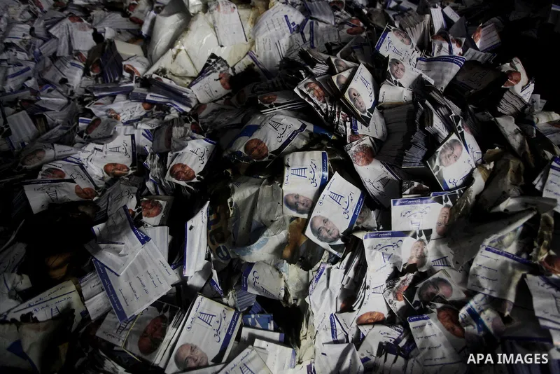 A man shows flyers of presidential candidate Ahmed Shafiq at the scene of the burnt campaign headquarters of Shafiq in Cairo May 29, 2012. A group of Egyptian protesters set fire to the headquarters on Monday, the state...