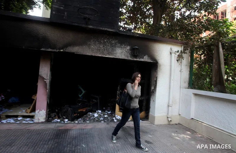 Egyptian woman walks in front of the burnt campaign headquarters of candidate and former prime minister Ahmed Shafiq in Cairo May 29, 2012. A group of Egyptian protesters set fire to the headquarters on Monday, the state...