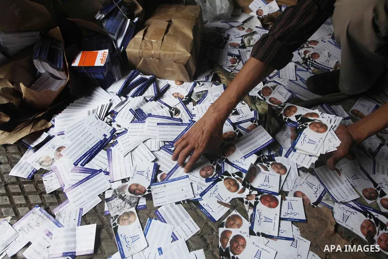 A man shows flyers of presidential candidate Ahmed Shafiq at the scene of the burnt campaign headquarters of Shafiq in Cairo May 29, 2012. A group of Egyptian protesters set fire to the headquarters on Monday, the state...
