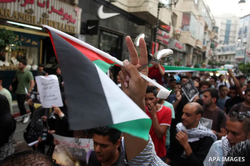 Palestinian protestor flashs the sign for victory as they bang pots with kitchen utensils during a demonstration in the West Bank city of Ramallah on May 29, 2012 in support of Palestinian prisoners Akram al-Rikhawi (por...