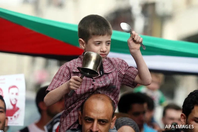 Palestinian child bangs on pot during a demonstration in the West Bank city of Ramallah on May 29, 2012 in support of Palestinian prisoners Akram al-Rikhawi (portrait) and Mahmoud al-Sarsak who are still refusing food a...