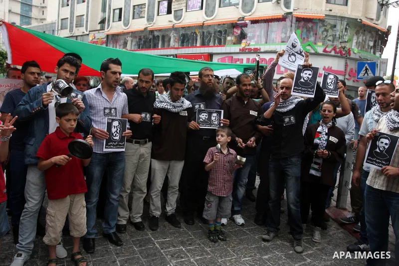 Palestinian protesters hold pictures of prisoners, as they bang pots with kitchen utensils during a demonstration in the West Bank city of Ramallah on May 29, 2012 in support of Palestinian prisoners Mahmoud al-Sarsak an...