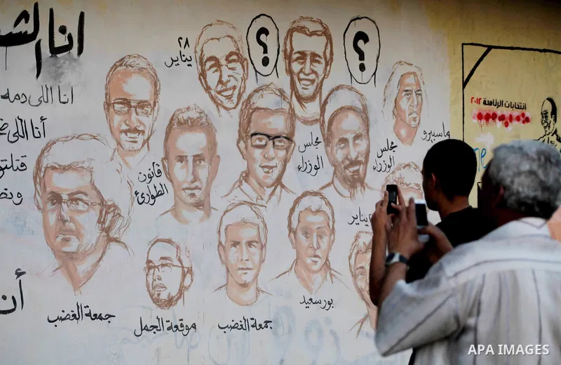 Egyptians walk in front of a wall sprayed graffiti at Tahrir Square in Cairo May 30, 2012. An arson attack on the headquarters of one of the two candidates in Egypt's presidential election has marred campaigning for the...
