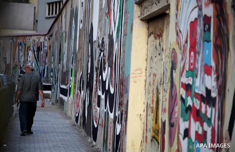 Egyptians walk in front of a wall sprayed graffiti at Tahrir Square in Cairo May 30, 2012. An arson attack on the headquarters of one of the two candidates in Egypt's presidential election has marred campaigning for the...