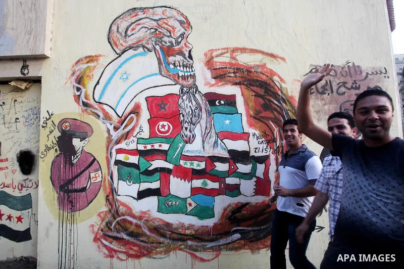 Egyptians walk in front of a wall sprayed graffiti at Tahrir Square in Cairo May 30, 2012. An arson attack on the headquarters of one of the two candidates in Egypt's presidential election has marred campaigning for the...