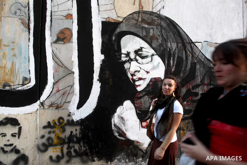 Egyptians walk in front of a wall sprayed graffiti at Tahrir Square in Cairo May 30, 2012. An arson attack on the headquarters of one of the two candidates in Egypt's presidential election has marred campaigning for the...