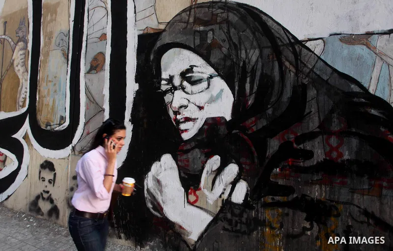 Egyptians walk in front of a wall sprayed graffiti at Tahrir Square in Cairo May 30, 2012. An arson attack on the headquarters of one of the two candidates in Egypt's presidential election has marred campaigning for the...