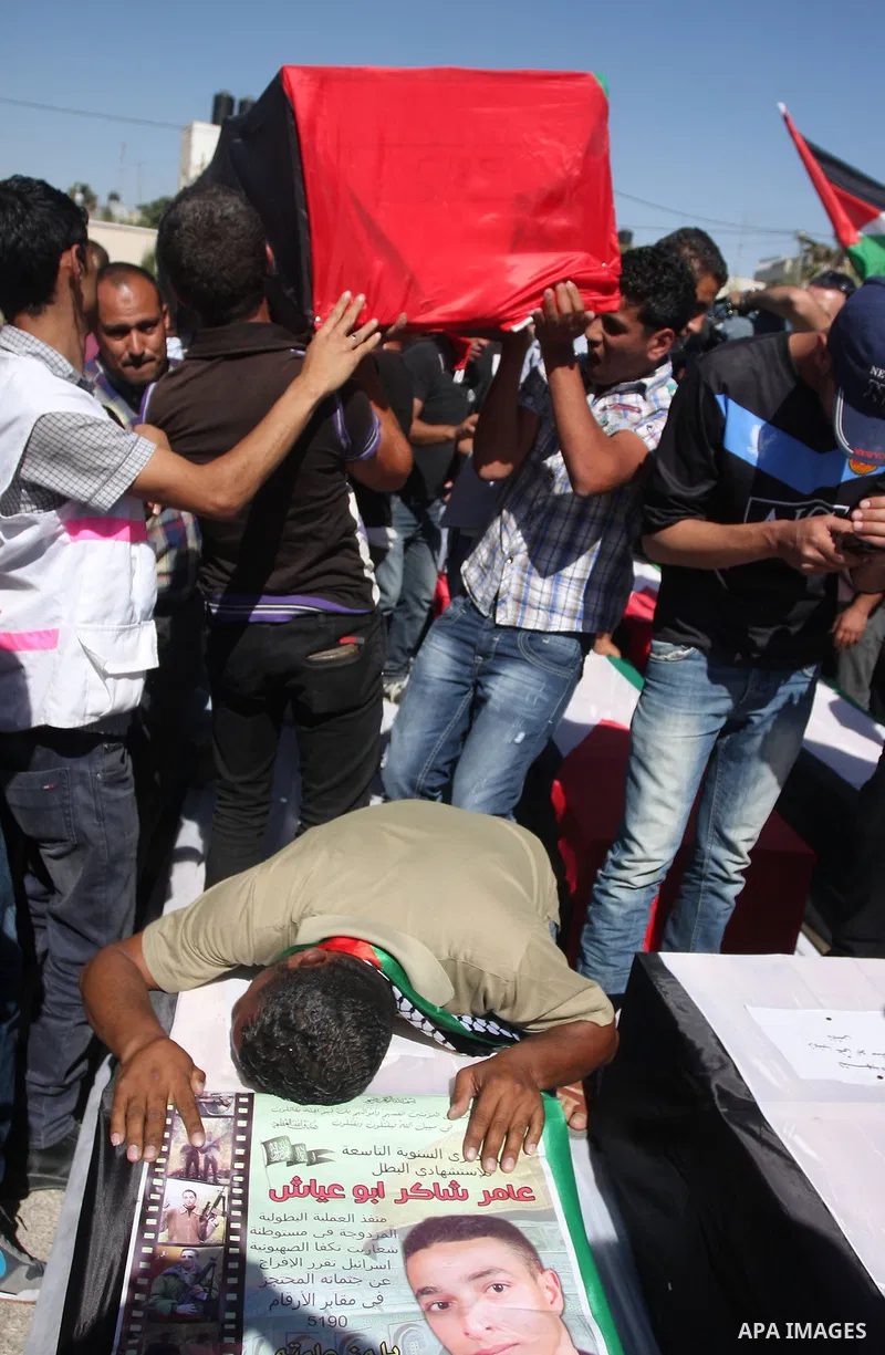 Palestinian man mourn over a flag-draped coffin prior to the funeral of 91 Palestinians whose remains were returned by Israel at the Palestinian leadership headquarters in the West Bank city of Ramallah on May 31, 2012....