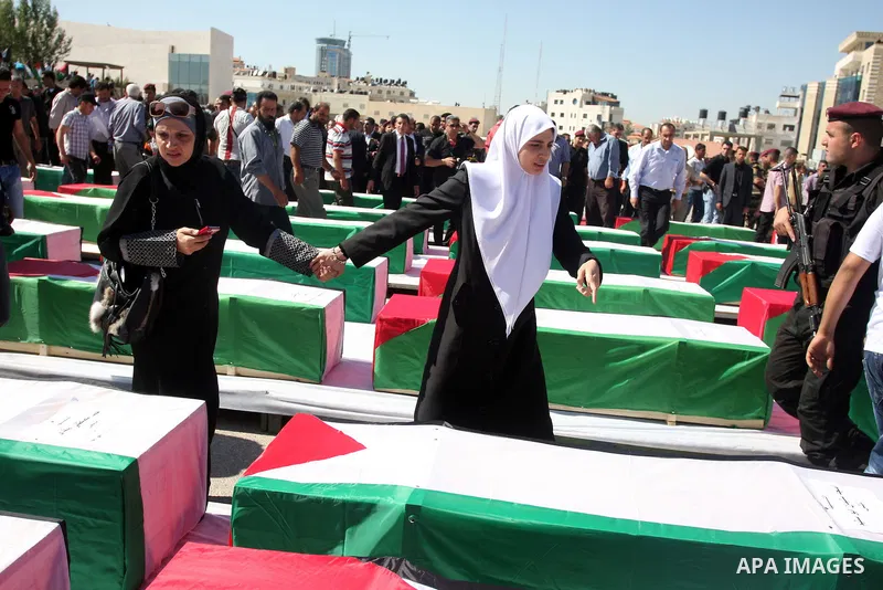 Palestinians pray over flag-draped coffins during the funeral of 91 Palestinians whose remains were returned by Israel at the Palestinian leadership headquarters in the West Bank city of Ramallah on May 31, 2012. Israel...