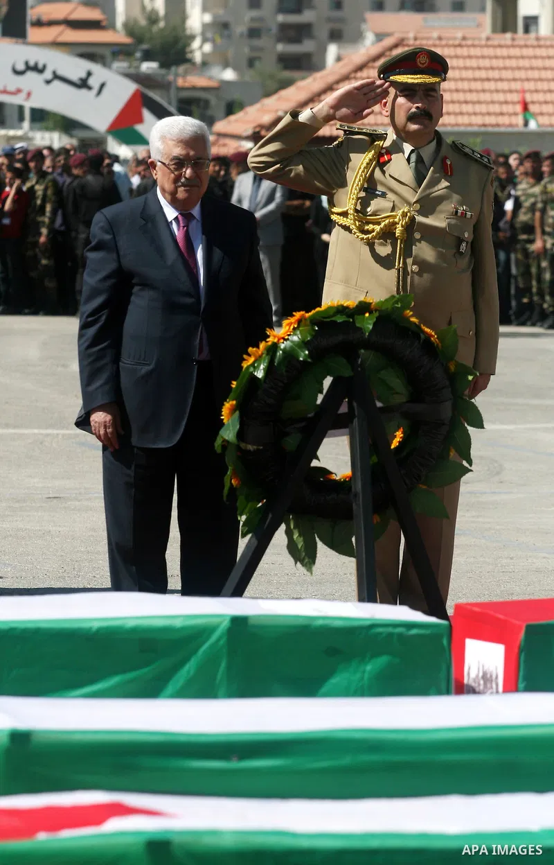 Palestinian President Mahmoud Abbas (C) prays over flag-draped coffins during the funeral of 91 Palestinians whose remains were returned by Israel at the Palestinian leadership headquarters in the West Bank city of Ramal...