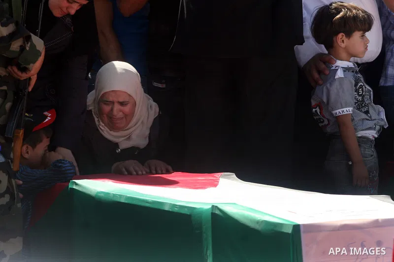 Palestinian woman mourn over a flag-draped coffin prior to the funeral of 91 Palestinians whose remains were returned by Israel at the Palestinian leadership headquarters in the West Bank city of Ramallah on May 31, 2012...