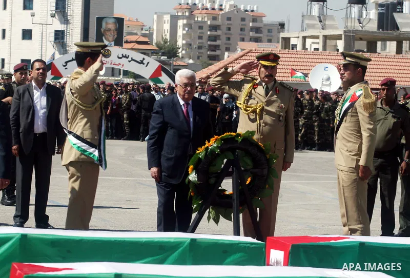 Palestinian President Mahmoud Abbas (C) prays over flag-draped coffins during the funeral of 91 Palestinians whose remains were returned by Israel at the Palestinian leadership headquarters in the West Bank city of Ramal...