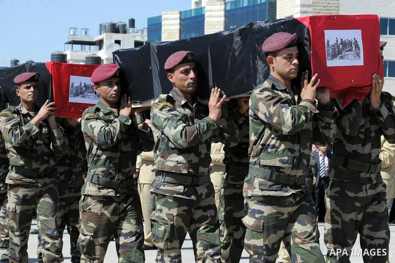 Members of the Palestinian security forces carry flag-covered coffins containing the remains of Palestinian militants during an official ceremony in the West Bank city of Ramallah May 31, 2012. The remains of 91 Palestin...