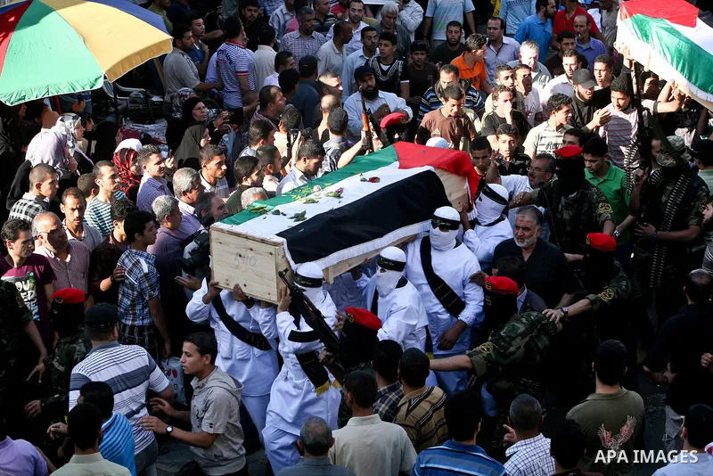 Relatives and masked Palestinian militants carry flag-drapped coffins containing the remains of Palestinian militants after the arrival of the caskets in Gaza City, 31 May 2012. Israel handed over the remains of dozens o...
