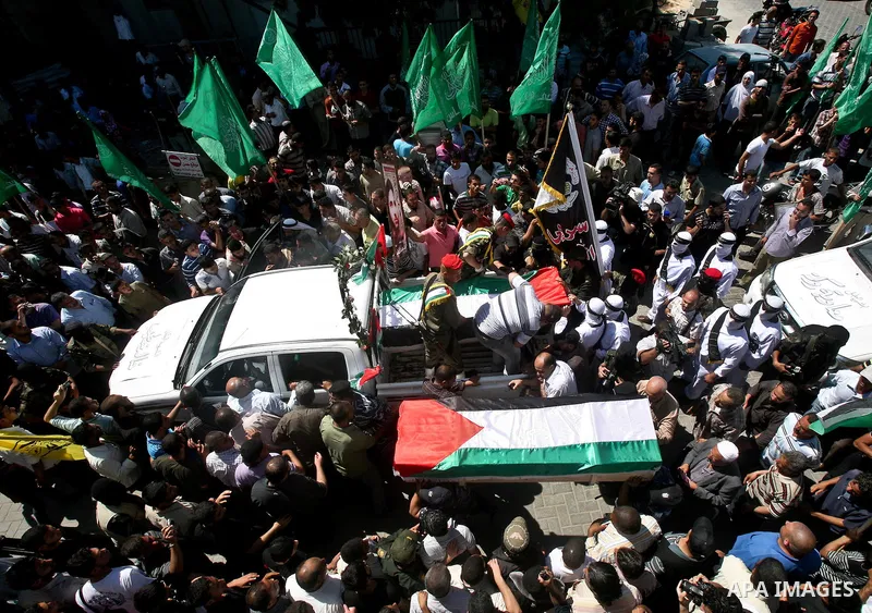 Relatives and masked Palestinian militants carry flag-drapped coffins containing the remains of Palestinian militants after the arrival of the caskets in Gaza City, 31 May 2012. Israel handed over the remains of dozens o...
