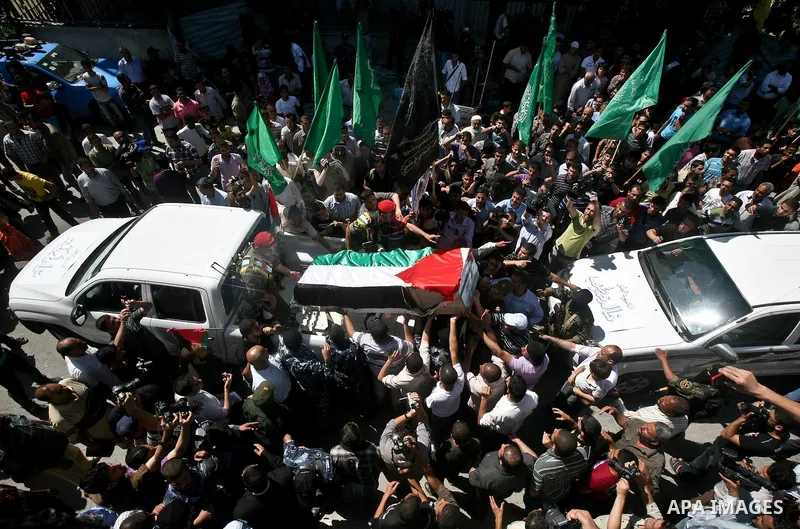 Relatives and masked Palestinian militants carry flag-drapped coffins containing the remains of Palestinian militants after the arrival of the caskets in Gaza City, 31 May 2012. Israel handed over the remains of dozens o...