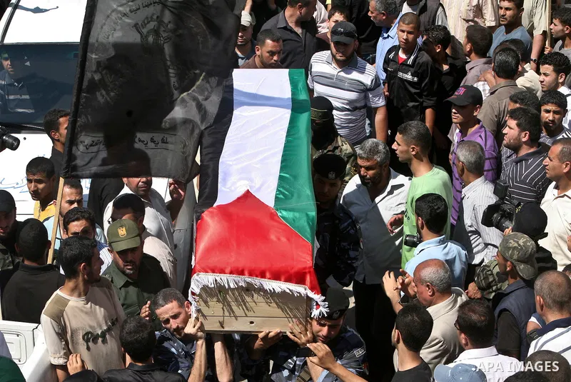 Relatives and masked Palestinian militants carry flag-drapped coffins containing the remains of Palestinian militants after the arrival of the caskets in Gaza City, 31 May 2012. Israel handed over the remains of dozens o...