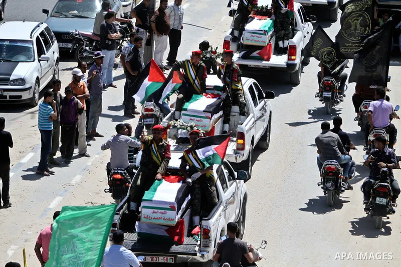 Relatives and masked Palestinian militants carry flag-drapped coffins containing the remains of Palestinian militants after the arrival of the caskets in Gaza City, 31 May 2012. Israel handed over the remains of dozens o...