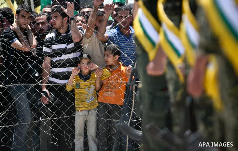 Palestinians wait as trucks carrying coffins containing the remains of bodies of 12 Palestinian militants transferred from Israel to the Palestinians arrive in the Gaza Strip through Erez crossing, in Beit Hanoun, Thursd...