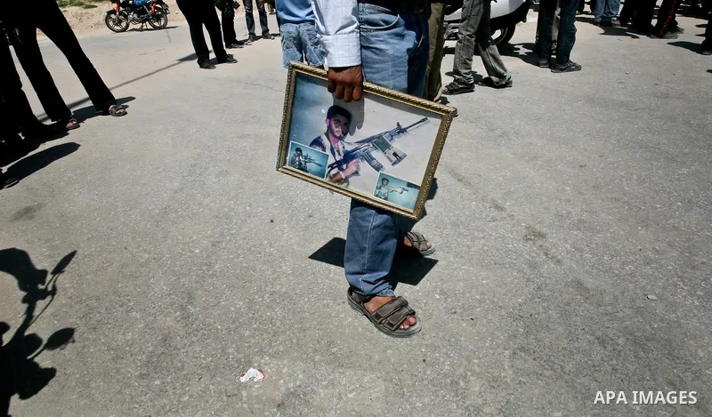 Palestinians wait as trucks carrying coffins containing the remains of bodies of 12 Palestinian militants transferred from Israel to the Palestinians arrive in the Gaza Strip through Erez crossing, in Beit Hanoun, Thursd...