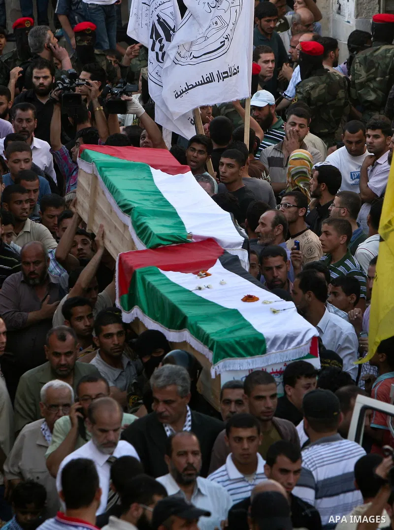 Relatives and masked Palestinian militants carry flag-drapped coffins containing the remains of Palestinian militants after the arrival of the caskets in Gaza City, 31 May 2012. Israel handed over the remains of dozens o...