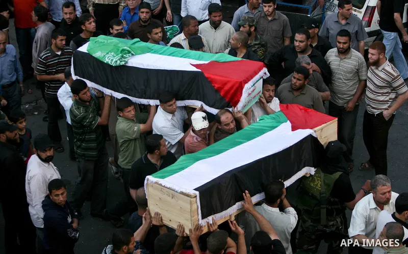 Relatives and masked Palestinian militants carry flag-drapped coffins containing the remains of Palestinian militants after the arrival of the caskets in Gaza City, 31 May 2012. Israel handed over the remains of dozens o...