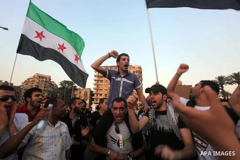 Syrians living in Egypt wave the revolutionary flag and shout slogans as they protest against the weekend massacre of Houla, in front of the Syrian embassy in Cairo, Egypt, 31 May 2012. A massacre was reported in the cen...