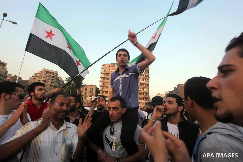 Syrians living in Egypt wave the revolutionary flag and shout slogans as they protest against the weekend massacre of Houla, in front of the Syrian embassy in Cairo, Egypt, 31 May 2012. A massacre was reported in the cen...