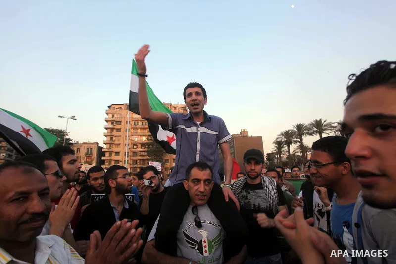 Syrians living in Egypt wave the revolutionary flag and shout slogans as they protest against the weekend massacre of Houla, in front of the Syrian embassy in Cairo, Egypt, 31 May 2012. A massacre was reported in the cen...
