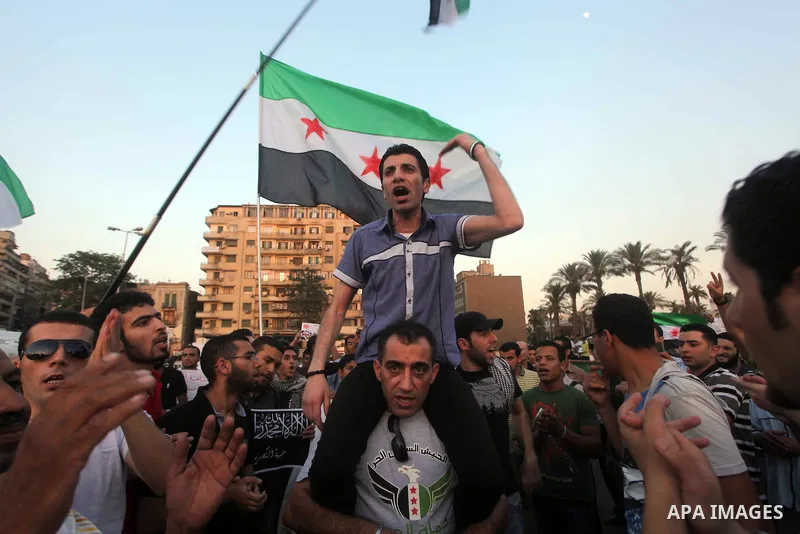 Syrians living in Egypt wave the revolutionary flag and shout slogans as they protest against the weekend massacre of Houla, in front of the Syrian embassy in Cairo, Egypt, 31 May 2012. A massacre was reported in the cen...
