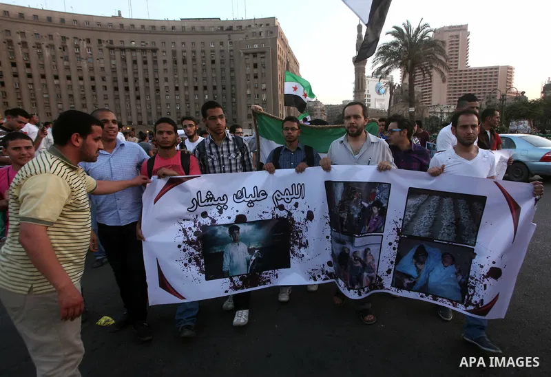 Syrians living in Egypt wave the revolutionary flag and shout slogans as they protest against the weekend massacre of Houla, in front of the Syrian embassy in Cairo, Egypt, 31 May 2012. A massacre was reported in the cen...