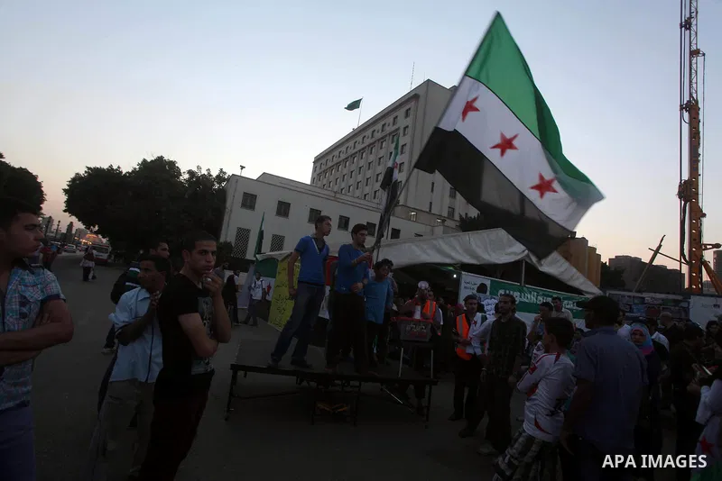 Protesters wave the revolutionary flag and shout slogans as they protest against the weekend massacre of Houla, in front of the Syrian embassy in Cairo, Egypt, 31 May 2012. A massacre was reported in the central Syrian c...