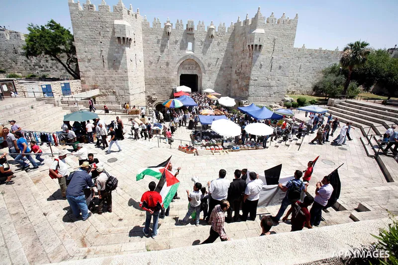 Palestinians hold national flag and shout slogans during a protest against continuing of 'Judaization of Jerusalem' by Jewish settlers and confiscating Palestinian lands at Al Tur and Damascus gate after Friday prayer in...