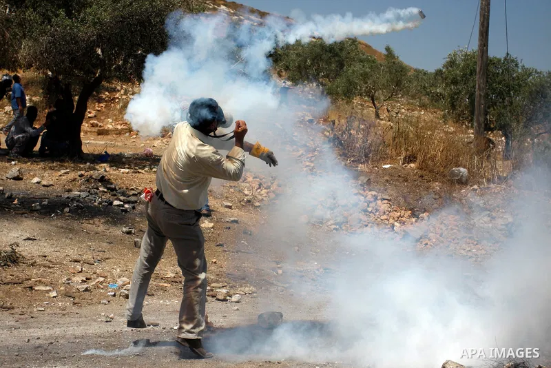 A Palestinian protester throws back a tear gas grenade towards Israeli soldiers during a demonstration against the expropriation of Palestinian land by Israel in the village of Kafr Qaddum, near the West Bank city of Nab...