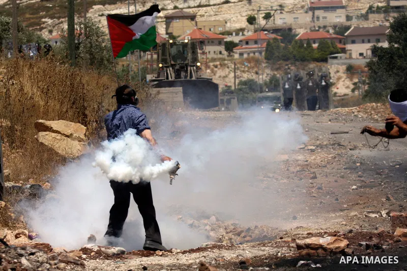A Palestinian protester throws back a tear gas grenade towards Israeli soldiers during a demonstration against the expropriation of Palestinian land by Israel in the village of Kafr Qaddum, near the West Bank city of Nab...
