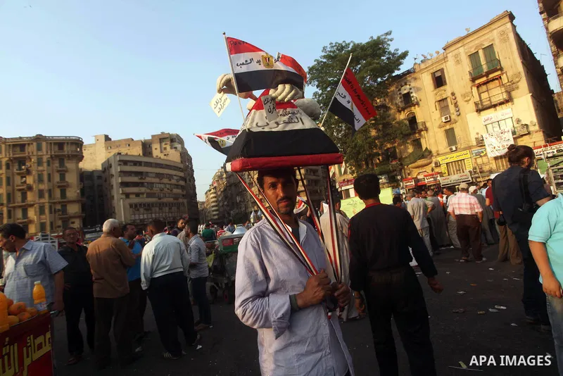 An Egyptian protester holds a hat in the shape of a pyramid bearing Egyptian flags and pro-democracy slogans during a demonstration against Egyptian presidential candidate Ahmed Shafiq in Tahrir Square decrying the resul...