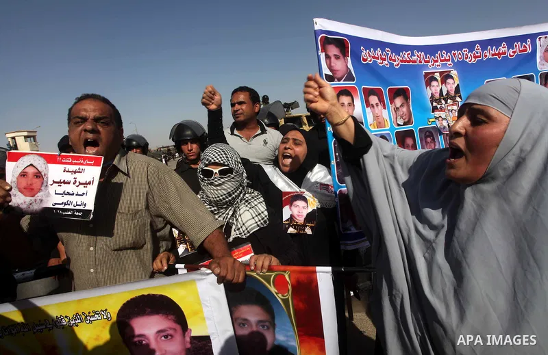 Egyptians Anti-Mubarak protester holding poster depicting youth killed during the uprising, reacts after a court sentenced deposed president Hosni Mubarak to life in prison, outside the police academy in Cairo, Egypt, 02...