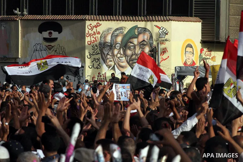 Egyptian protesters hold their national flag and effigies of the heads of former President Hosni Mubarak and his sons during a protest hours after the announcement of the verdict in their trial, in Tahrir square, Cairo,...