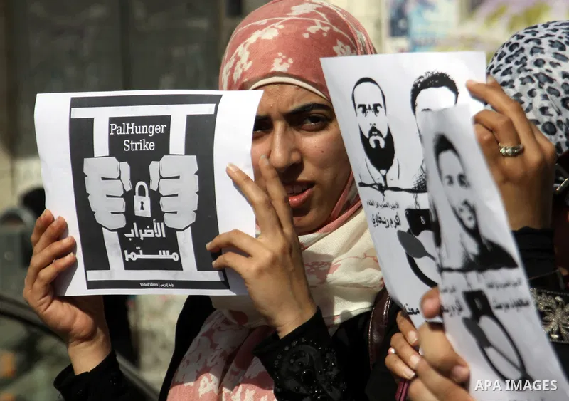 Palestinian protestors hold pictures of Palestinian prisoners Mahmoud al-Sarsak and Akram al-Rikhawi, whose are still refusing food for 80 days after a deal was made to end a mass prisoner hunger strike, during a demonst...