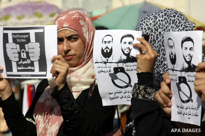 Palestinian protestors hold pictures of Palestinian prisoners Mahmoud al-Sarsak and Akram al-Rikhawi, whose are still refusing food for 80 days after a deal was made to end a mass prisoner hunger strike, during a demonst...