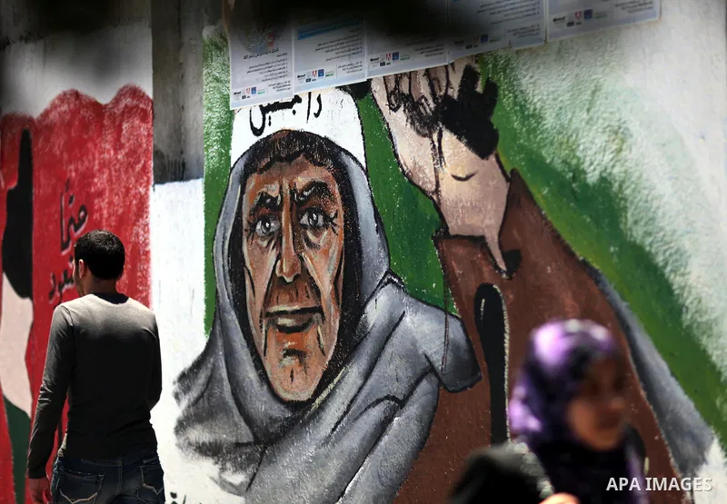 Palestinians walk past a mural of the Palestinian flag during the commemoration of the Naksa Day in Gaza City, June 5, 2012. Palestinians commemorate the Naksa Day, or the Setback, on Tuesday, marking the 45th anniversar...