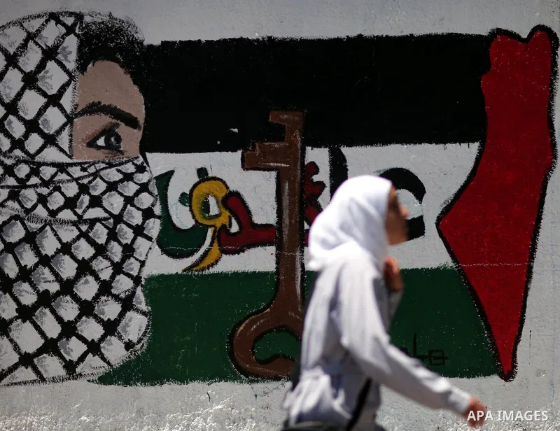 A Palestinian school girl walks past a mural of the Palestinian flag during the commemoration of the Naksa Day in Gaza City, June 5, 2012. Palestinians commemorate the Naksa Day, or the Setback, on Tuesday, marking the 4...