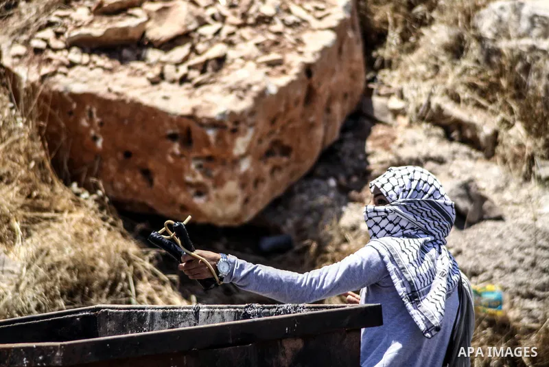A Palestinian protester throws stones at Israeli soldiers during clashes at the entrance to Ofer prison, near the West Bank city of Ramallah, on June 5, 2012 following a demonstration to mark "Naksa Day", the 44th annive...