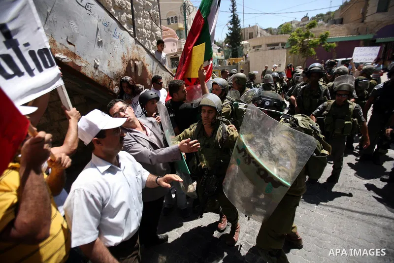 Palestinian protesters hold flags and banners during a demonstration against the Israeli occupation and to mark "Naksa Day", the 44th anniversary of the 1967 Six Day War, at the entrance of the old city near the settleme...