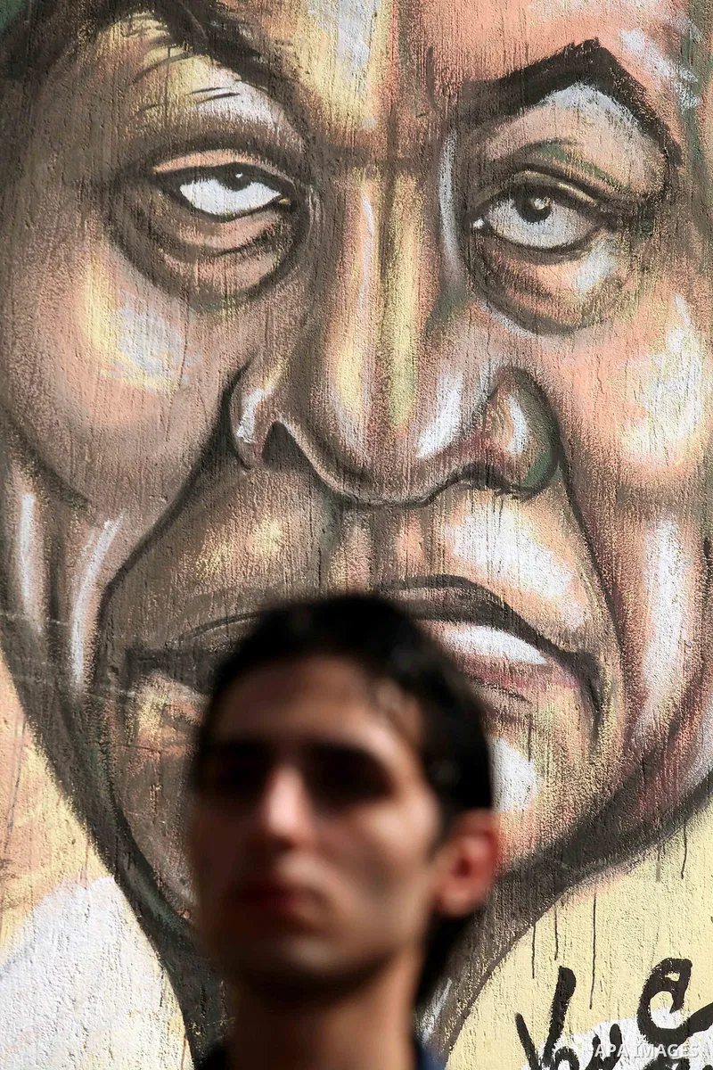 A man walks in front of a wall filled with graffiti against the Supreme Council of the Armed Forces (SCAF) near Tahrir Square during a demonstration in Cairo June 5, 2012. Activists urged Egyptians to turn out for a big...