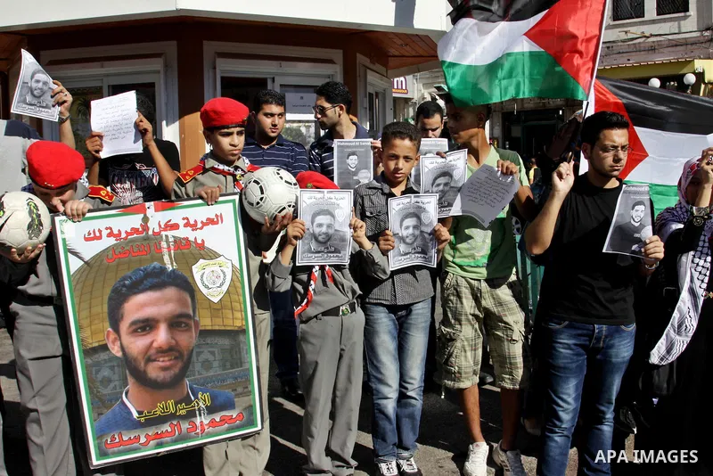 Palestinian protestors hold pictures of Palestinian prisoners Mahmoud al-Sarsak and Akram al-Rikhawi, whose are still refusing food for 80 days after a deal was made to end a mass prisoner hunger strike, during a demonst...
