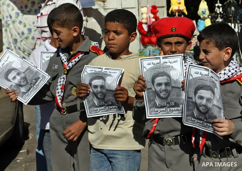 Palestinian protestors hold pictures of Palestinian prisoners Mahmoud al-Sarsak and Akram al-Rikhawi, whose are still refusing food for 80 days after a deal was made to end a mass prisoner hunger strike, during a demonst...