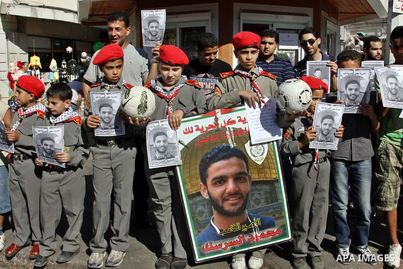 Palestinian protestors hold pictures of Palestinian prisoners Mahmoud al-Sarsak and Akram al-Rikhawi, whose are still refusing food for 80 days after a deal was made to end a mass prisoner hunger strike, during a demonst...