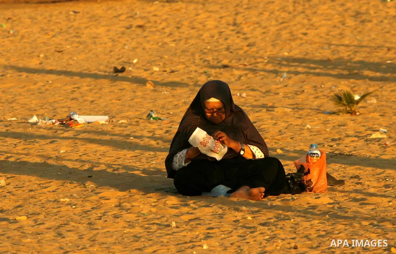 Palestinian woman embroiders at a park while children play during summer holiday in the Rafah refugee camp southern Gaza Strip on June 07, 2012. Photo by Eyad Al Baba